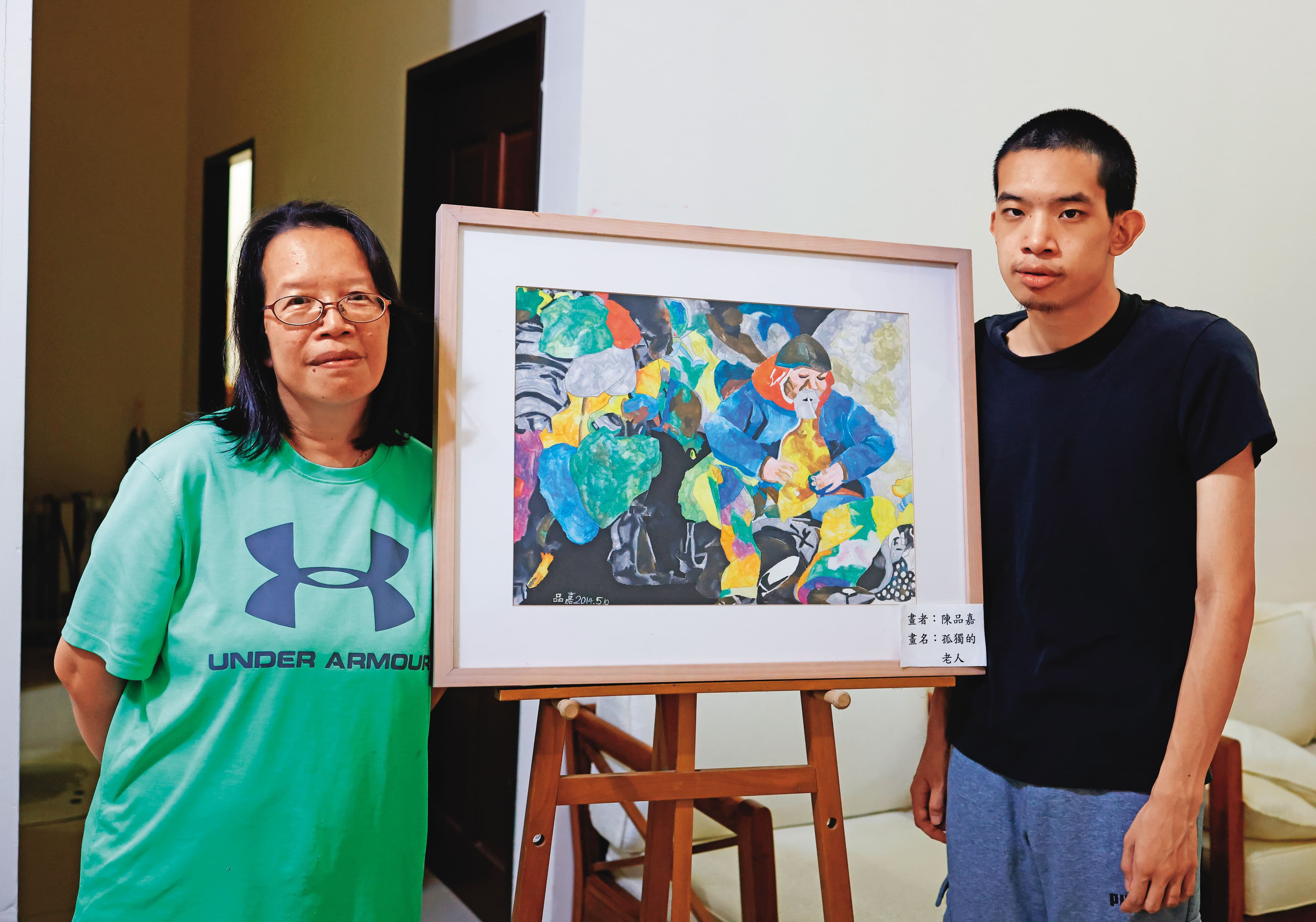董明芬與兒子，中間為兒子所繪作品。