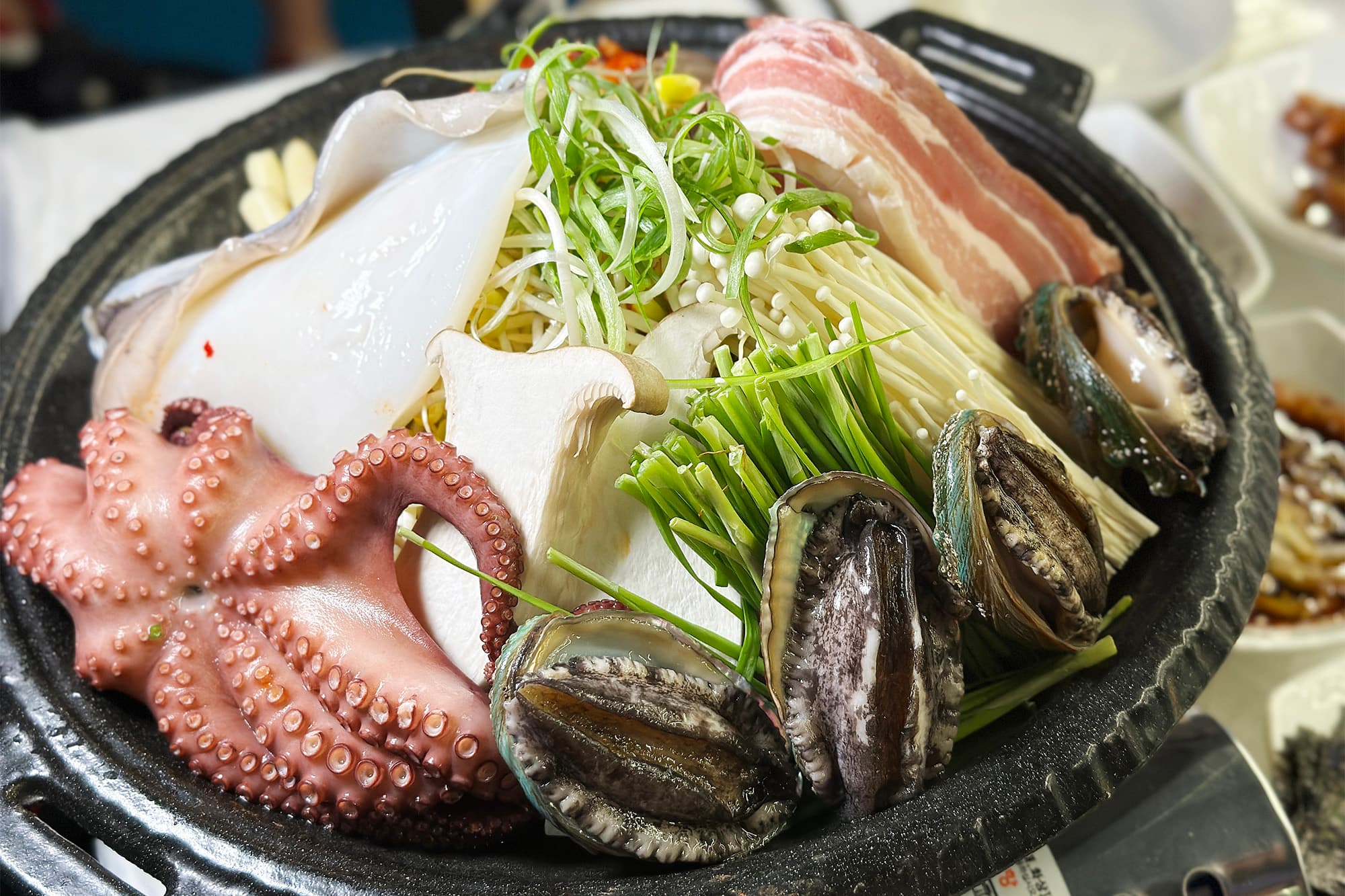 麗水章魚三合的標配是麗水特有小章魚，搭配豬五花、蔬菜等食材一起放在火鍋內拌煮。（78,000韓元/大份，約NT$1,950）