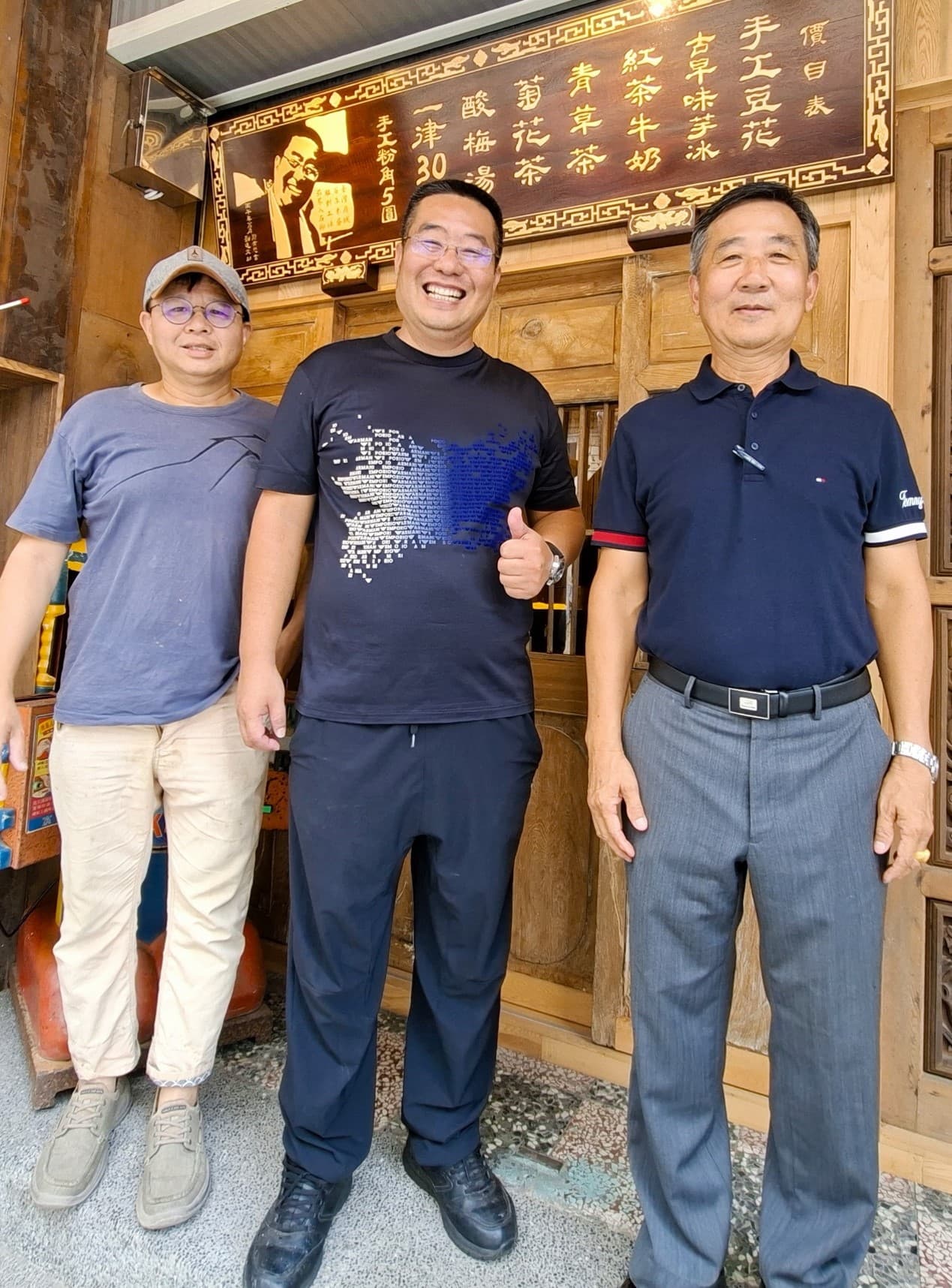 筑馨居豆花店的價目表由書藝家鄭有懋（右）題字，知名木雕藝師劉進文（左）以「茄苳入石柳」技法打造，兼具藝術與工藝價值。（張耘書拍攝，台南市政府觀光旅遊局提供）