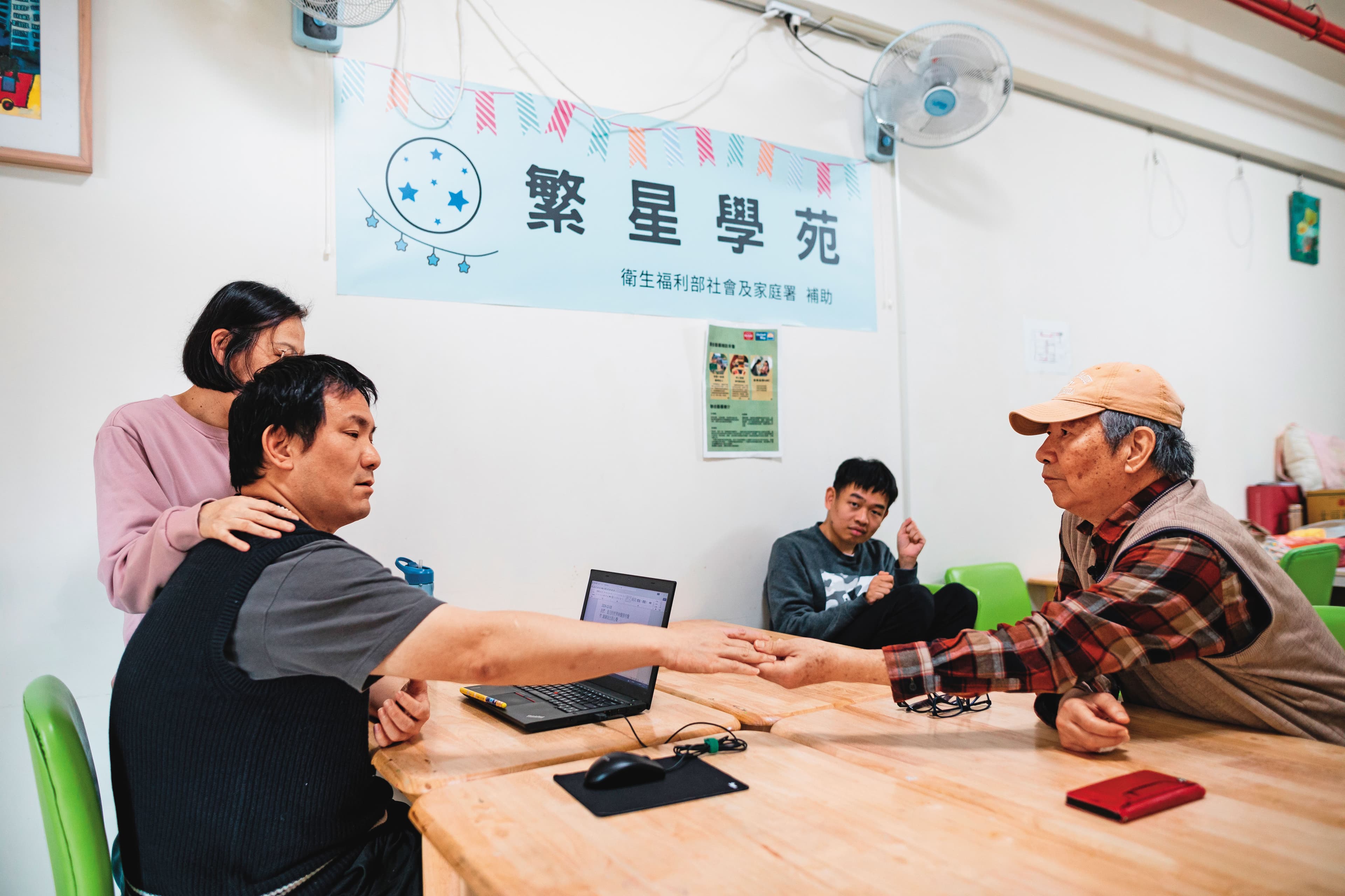 「繁星學院」裡，鄭文正（前右）的兒子（前左）在女老師扶著肩膀下，試著打字溝通。