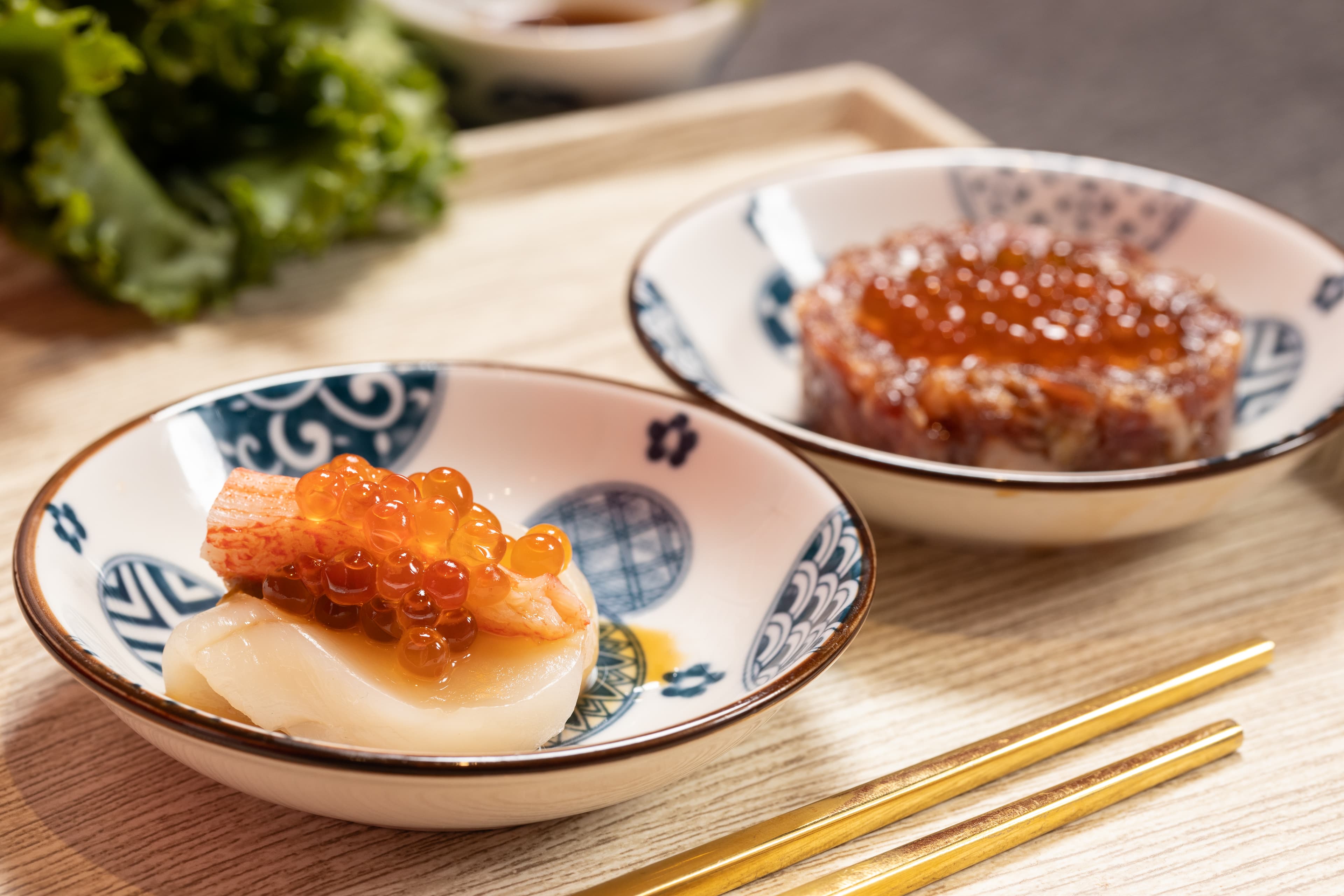 「招牌生食干貝漢堡」把北海道干貝夾入松葉蟹膏和蟳味棒，再澆淋鮭魚卵，一口吃，鮮味洶湧。（189元／份，圖左）