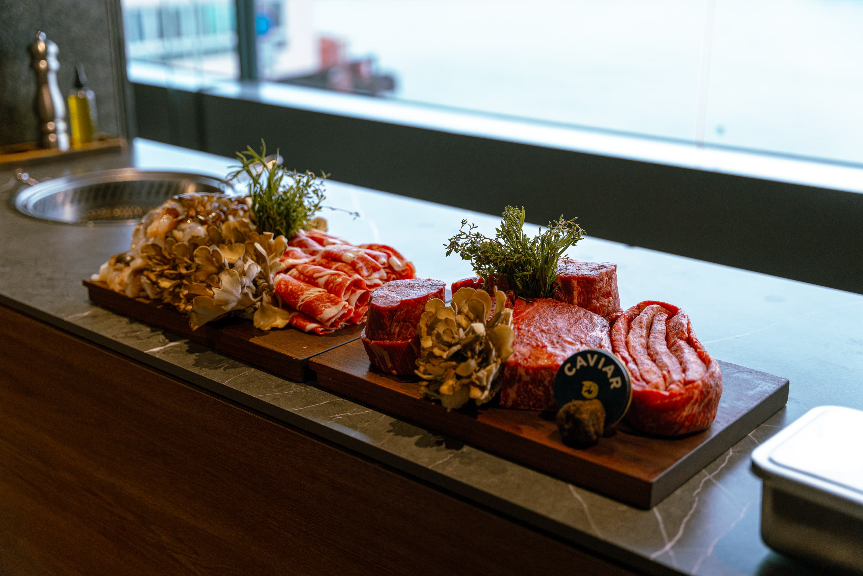 各種部位的韓牛、龍蝦與蔬菜食材在料理台上一字排開,誘人垂涎。