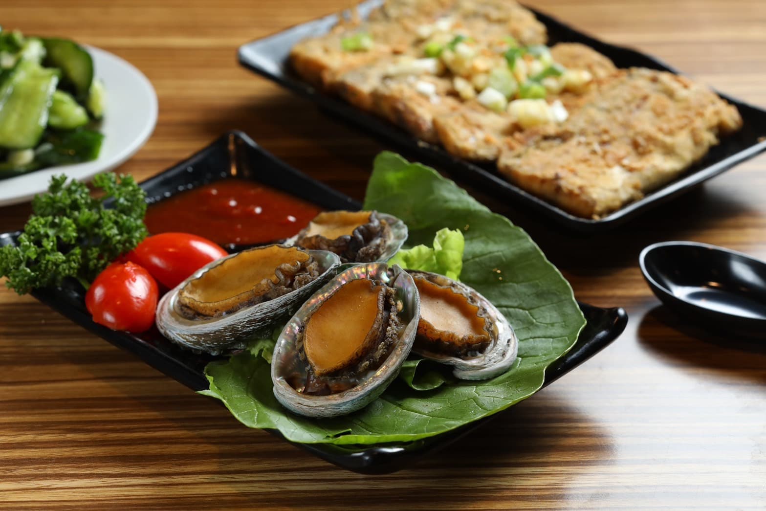口感Q彈帶鮮的「川燙活鮑魚」（前，239元／份）與香酥爽脆的 「炸白帶魚」（後，150元／份）
