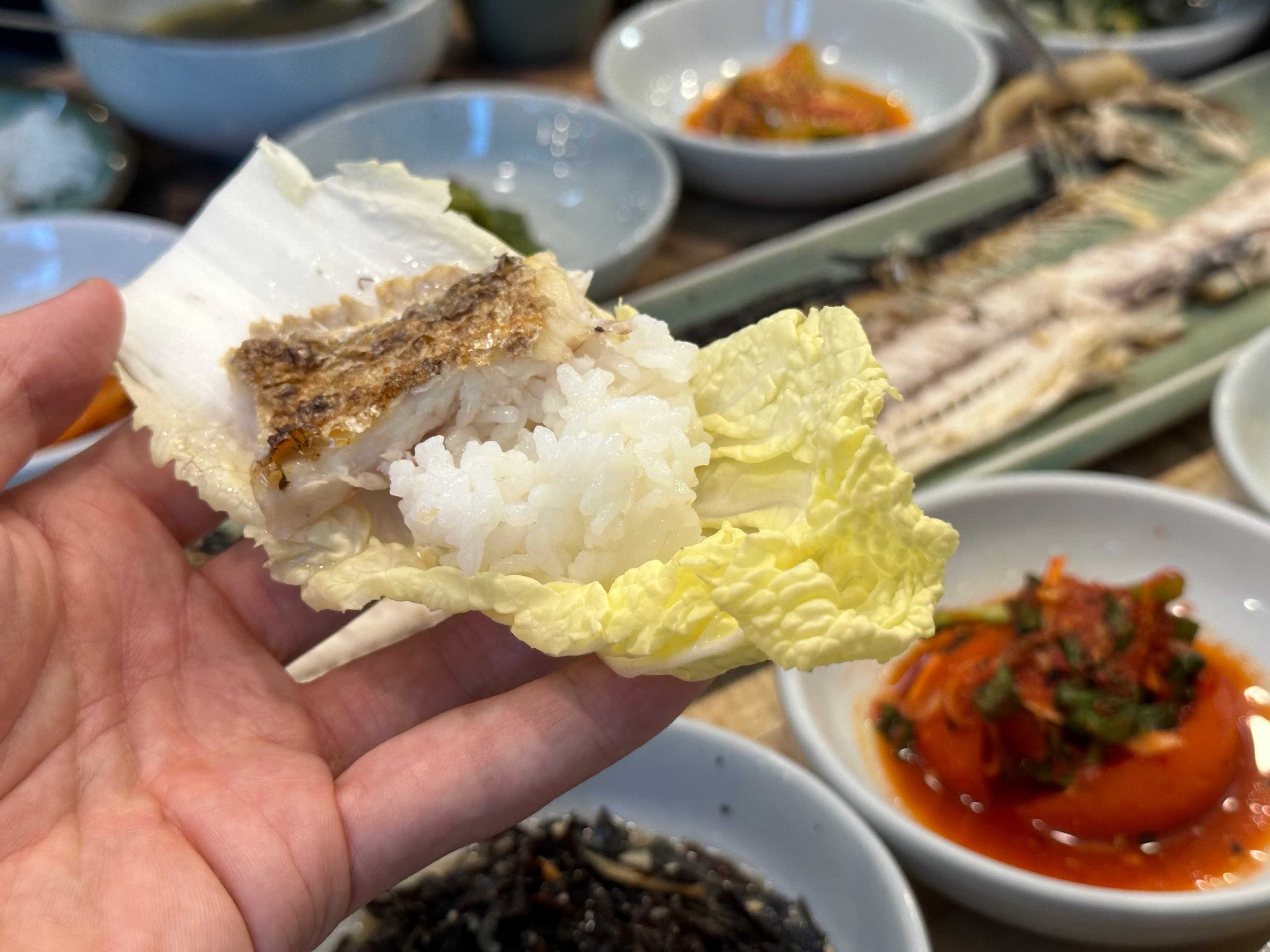 用生菜包著米飯和魚肉一口吃，風味清爽許多。