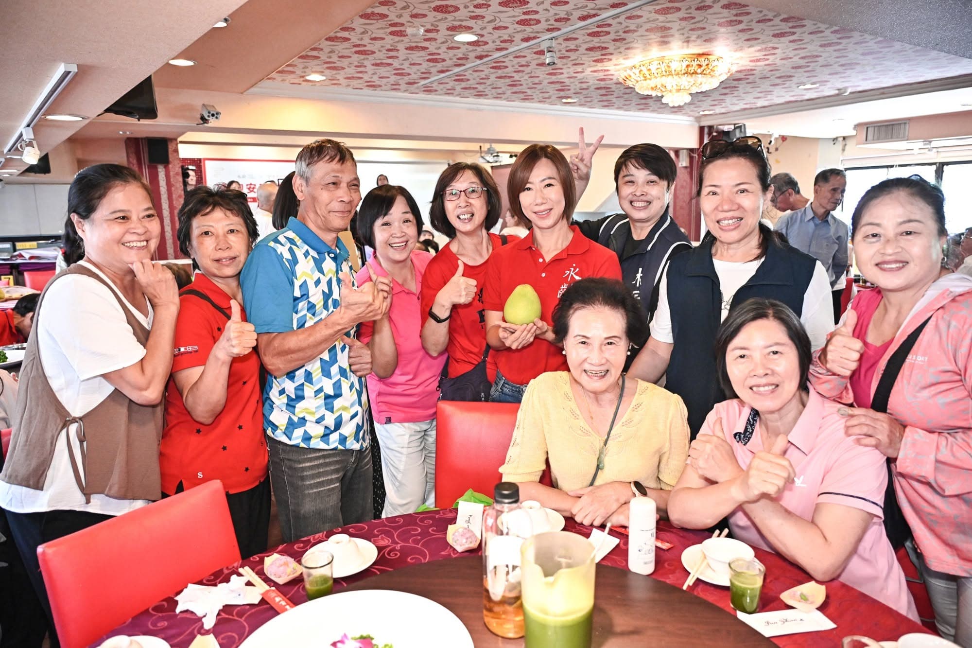 郭曉玲(後排右4)與長輩合影,並推廣集結50道營養料理的《美味食記》。(翻攝永齡基金會臉書)