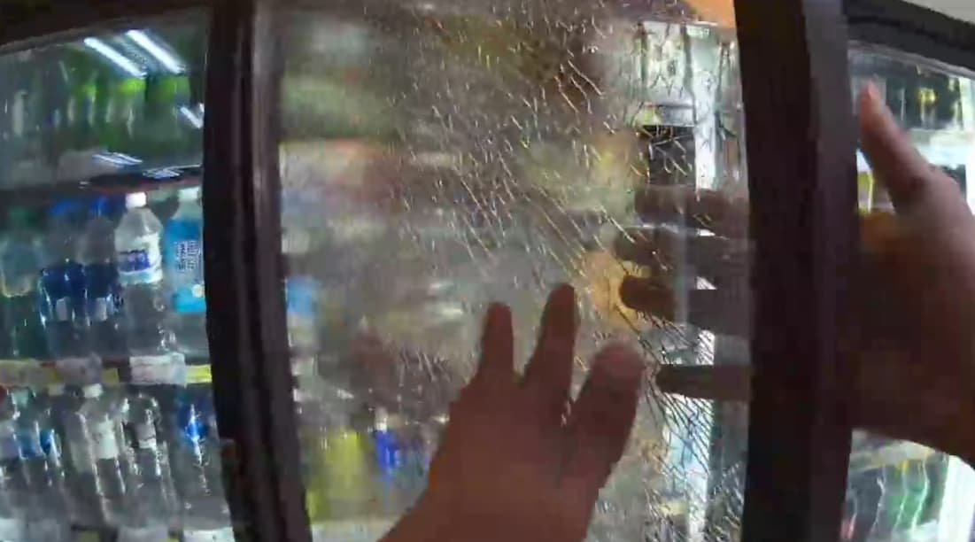 桃園一名裸男闖入超商後砸毀冰櫃玻璃門,隨後竟兀自坐在店外喝飲料。(翻攝畫面)